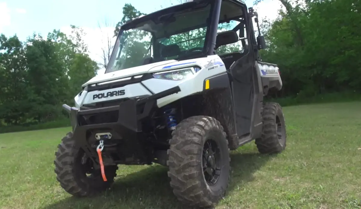 A Polaris Ranger XP Kinetic is parked on a green field.