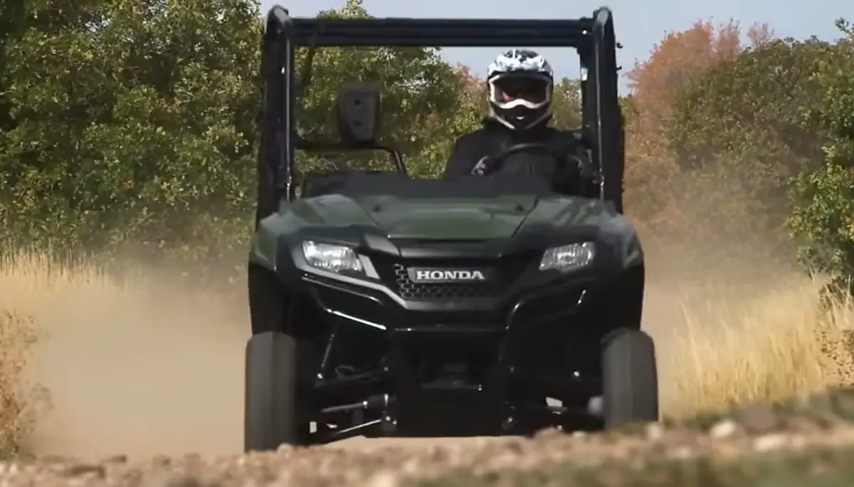 A Honda Pioneer 700 is being driven through a dirt road.