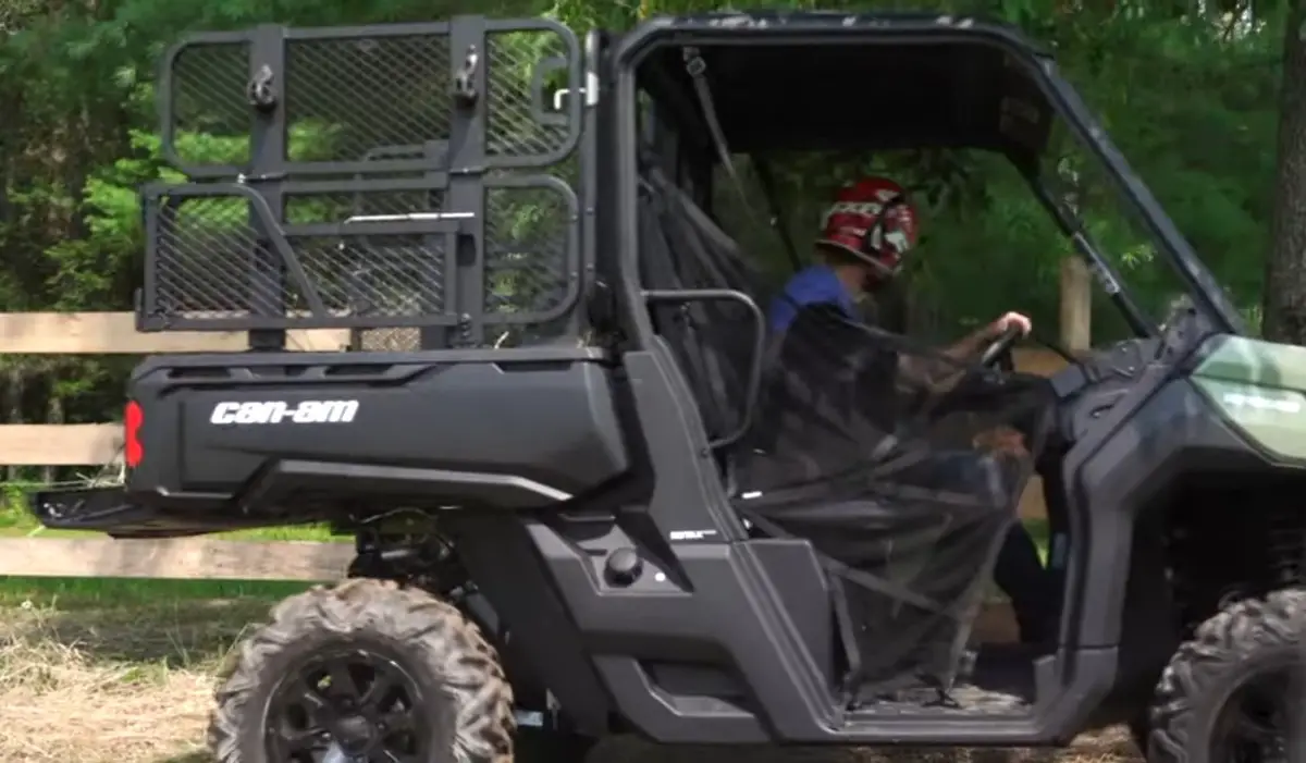 A Can-am defender is being driven through a farm.