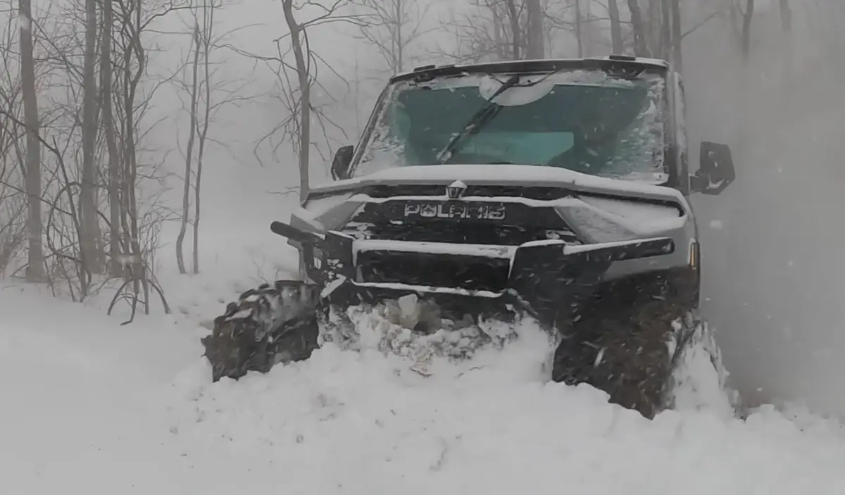 A Polaris Ranger NorthStar is being driven through a deep snow road.