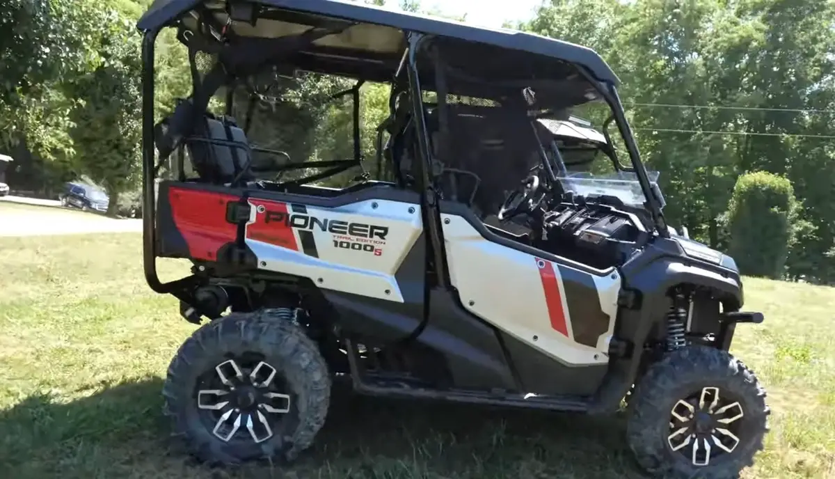 A Honda Pioneer 1000 is parked in a green field.