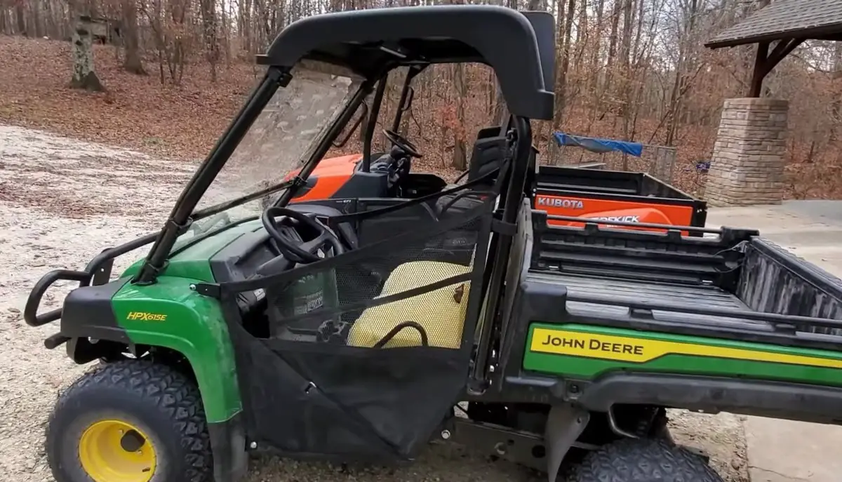 A John Deere HPX615E is parked in front of a building.