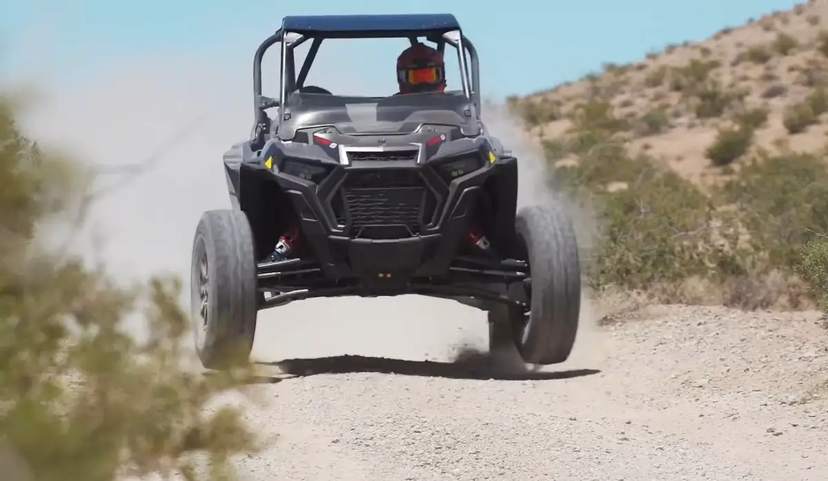 A Polaris RZR Turbo S is being driven through a desert road.