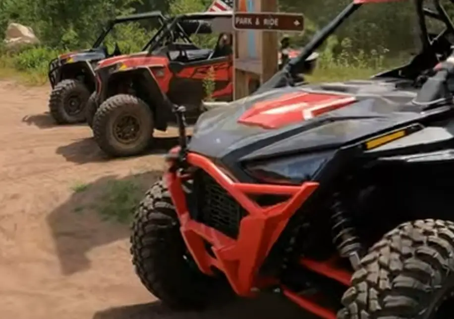 Three Polaris UTVs parked on a dirt surface in a row.