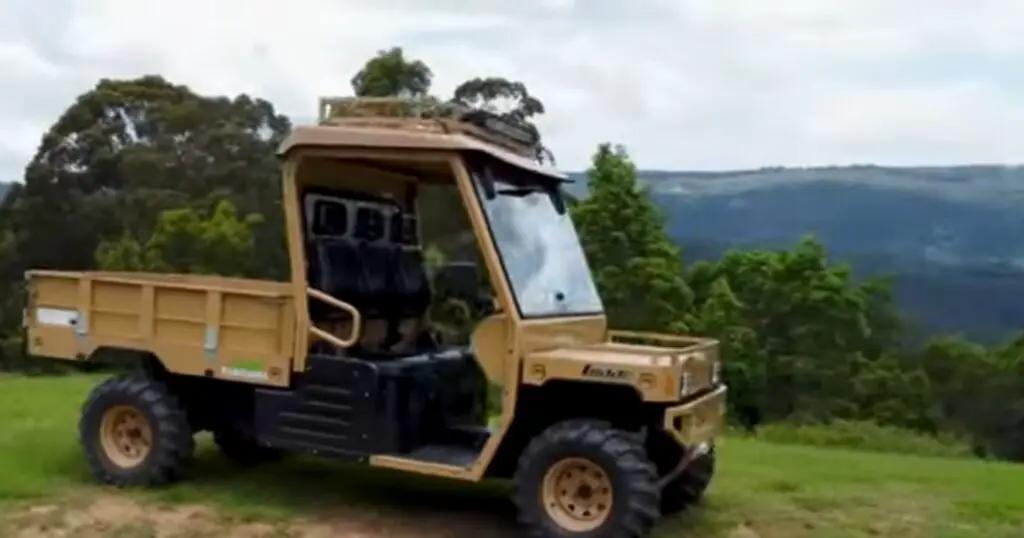 A Tuatara UTV is parked on a hill. In the background there are trees and mountains.