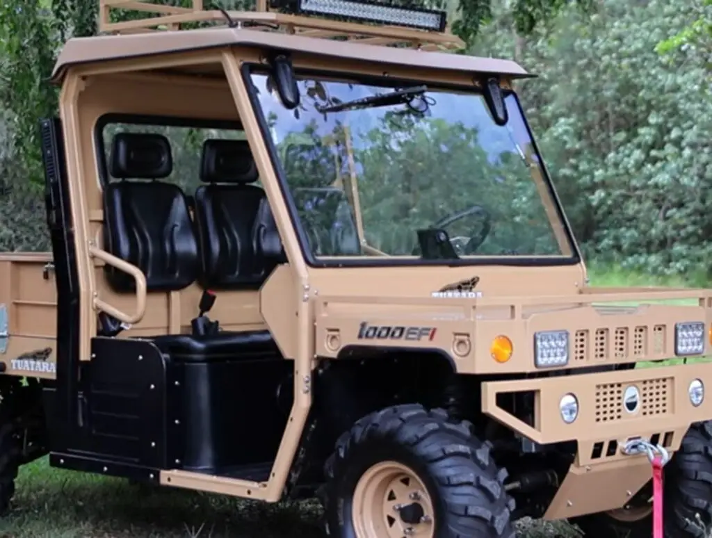 A Tuatara 1000 UTV is parked in a green field under a tree.