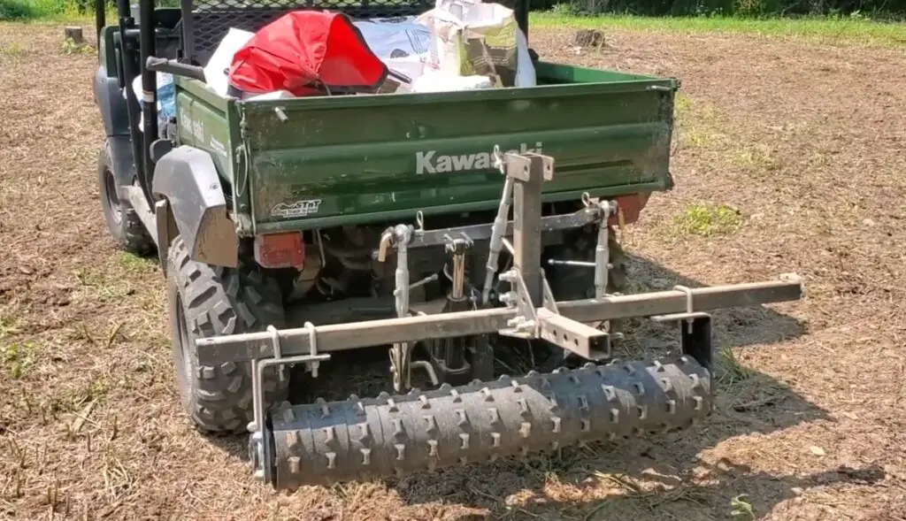 A Kawasaki UTV is parked on a farm field with food plot attachment.