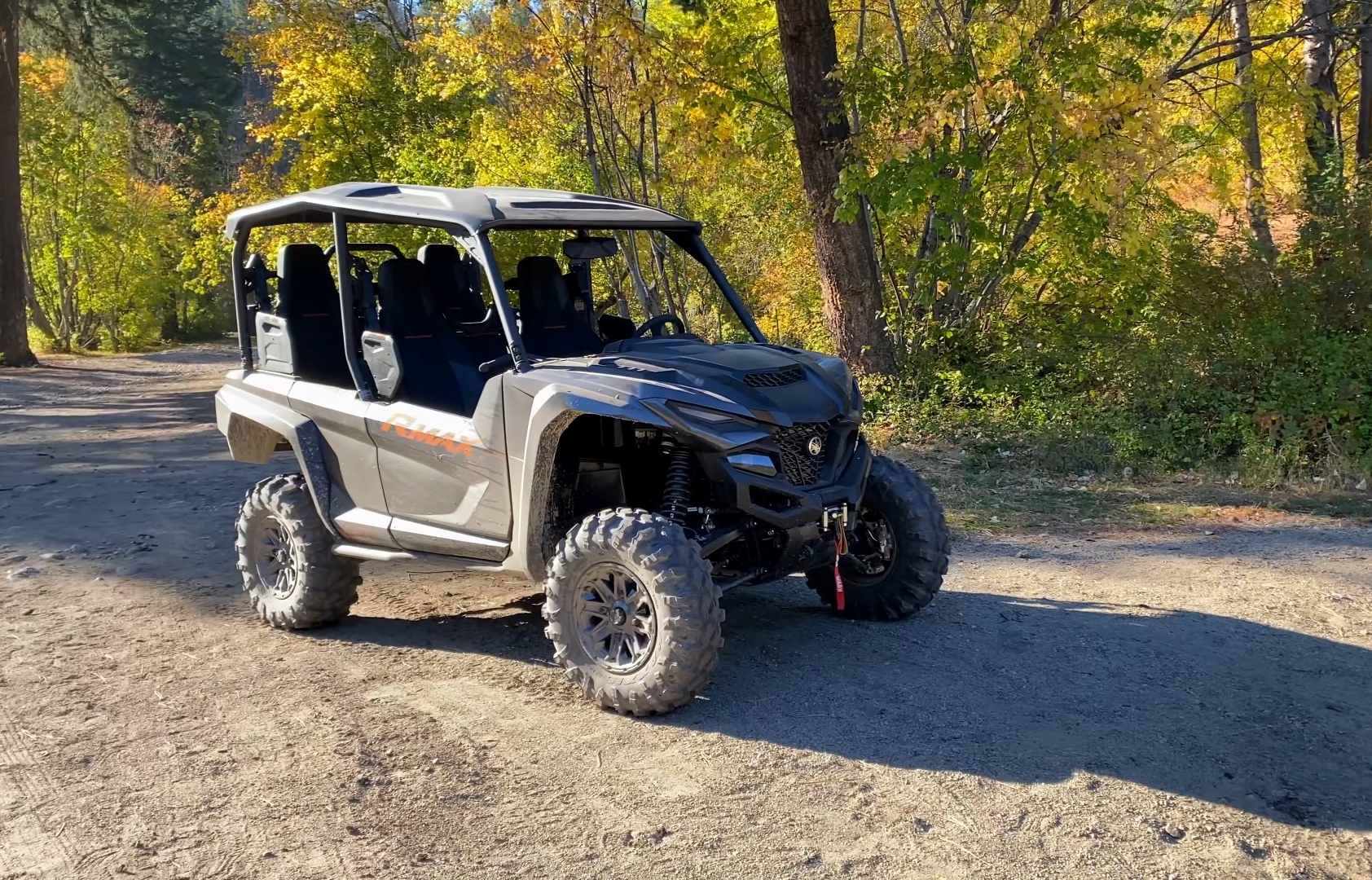 A Yamaha Wolverine RMAX4 1000 is parked on a dirt road close to a forest.