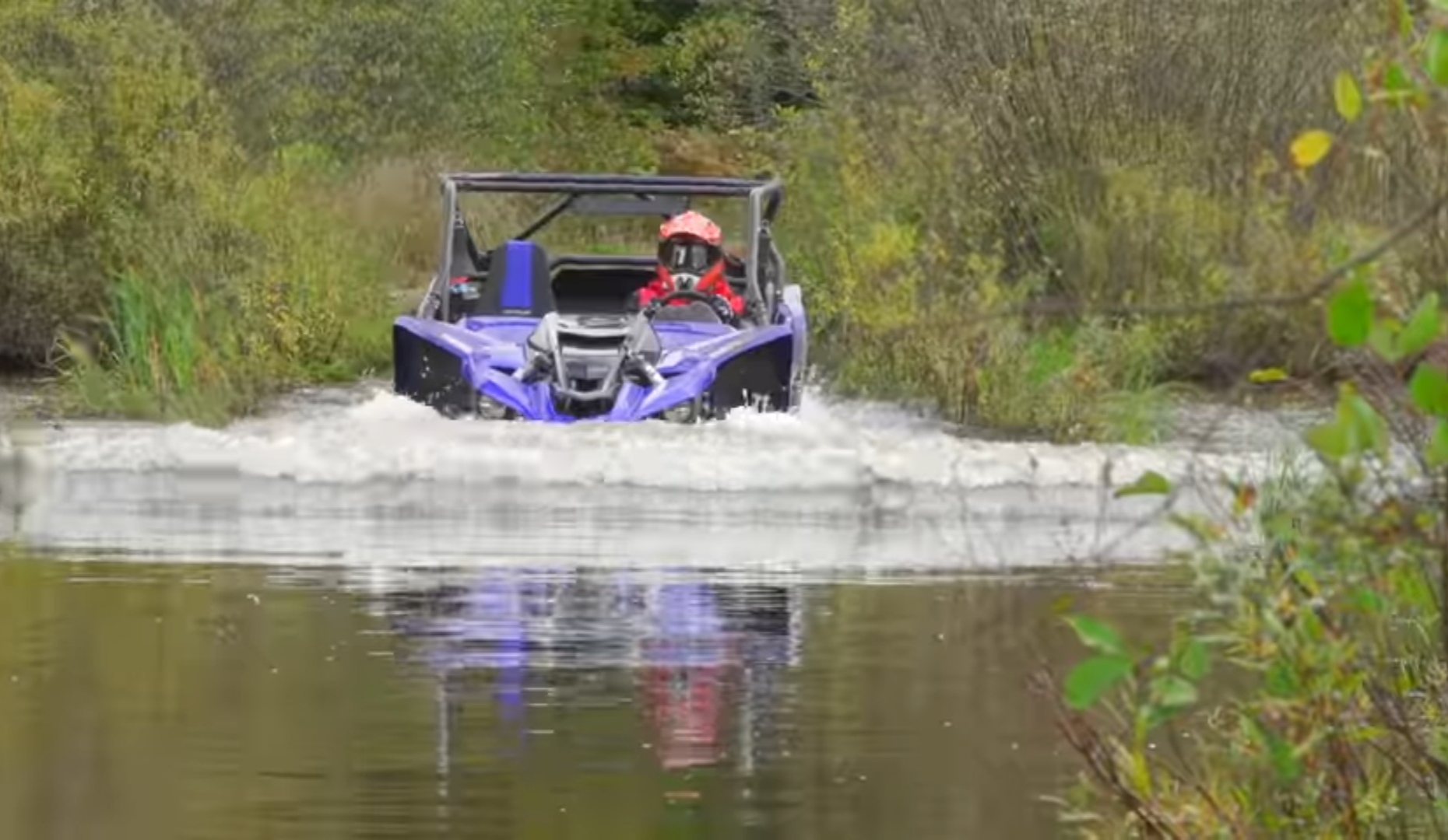 A Yamaha YXZ is being driven through a river.