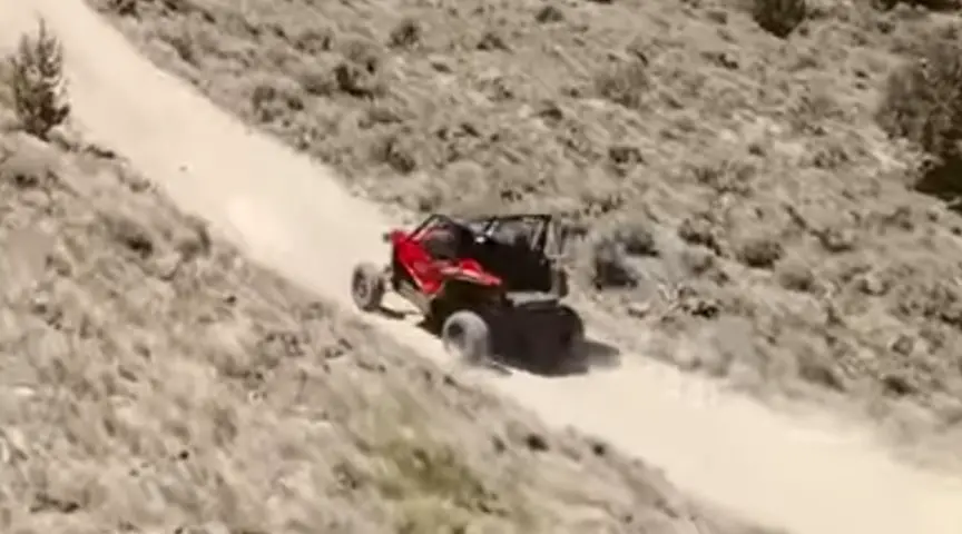 A Honda Talon 1000R is being driven through a dirt road 
