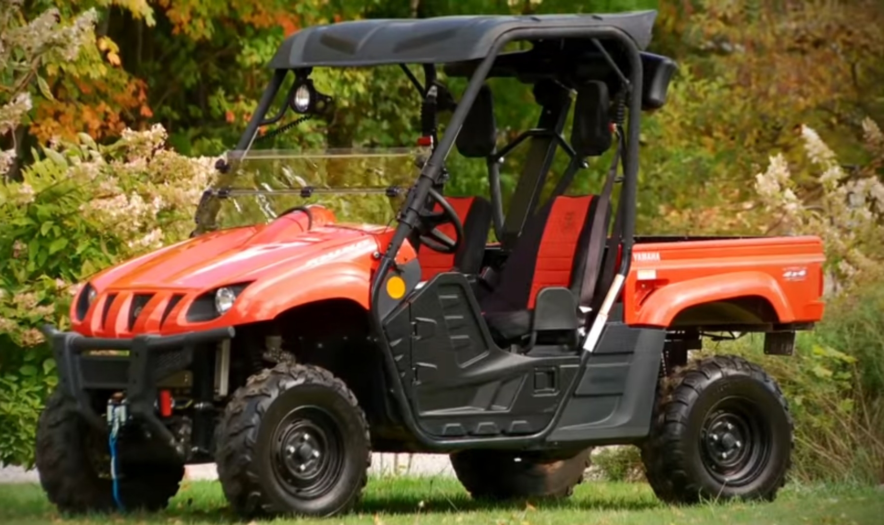 A red Yamaha Rhino 700 is parked in a flower garden.