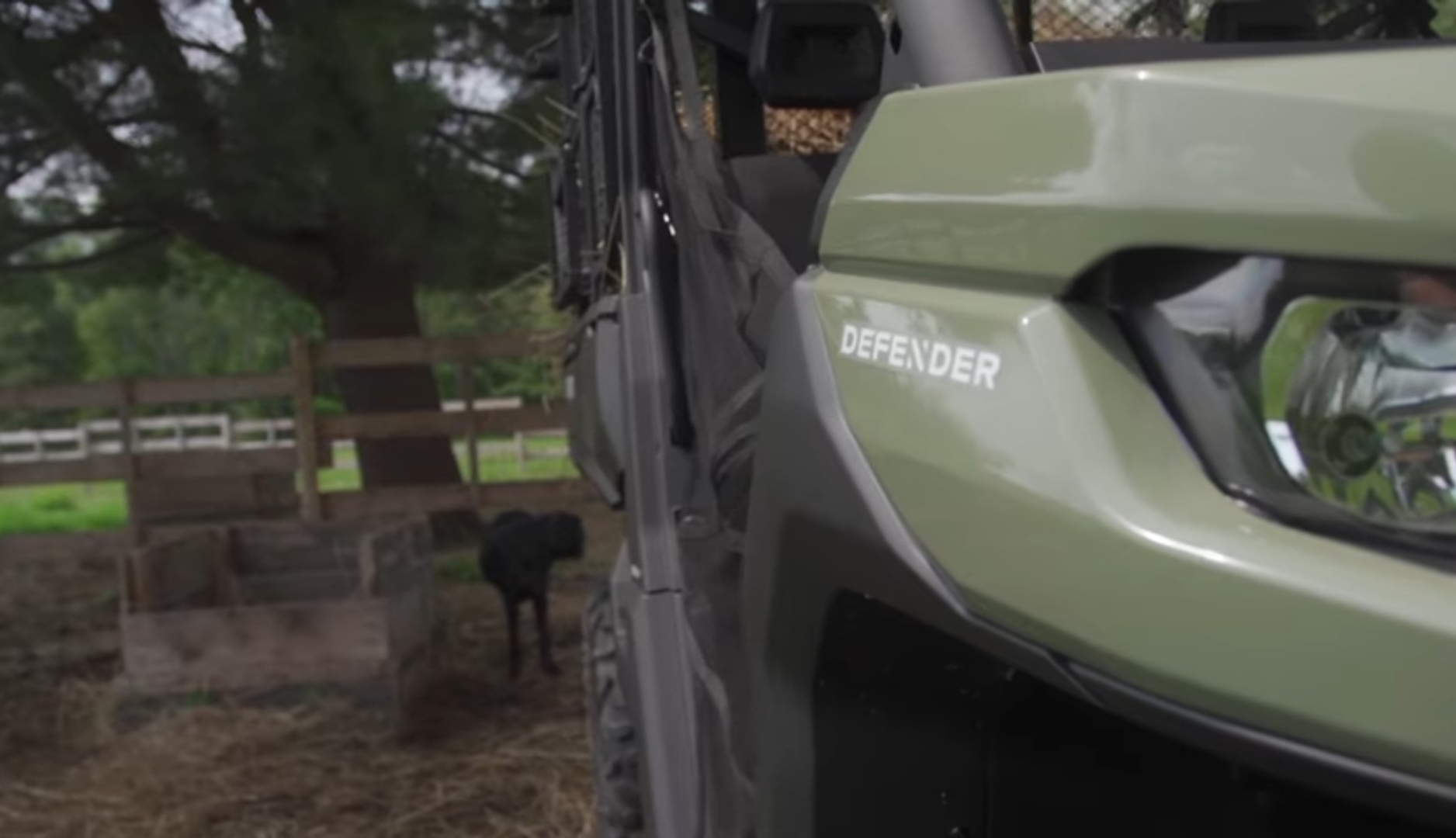 A Can-am defender pro XT is parked in a farm under some trees.