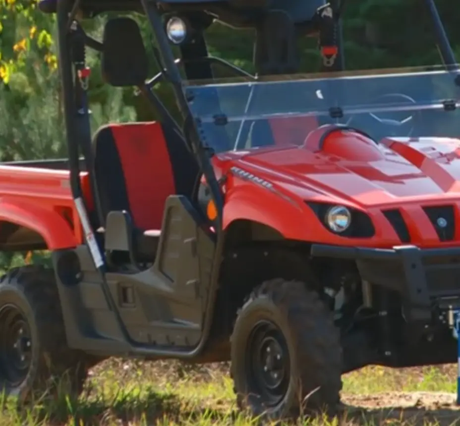 A red Yamaha Rhino 700 is parked on a grassy field.