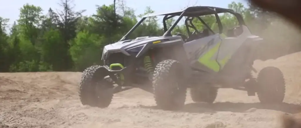 A Polaris RZR Is parked on sandy surface.