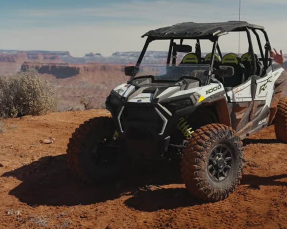 A Polaris RZR 1000 is parked on the top of a hill.