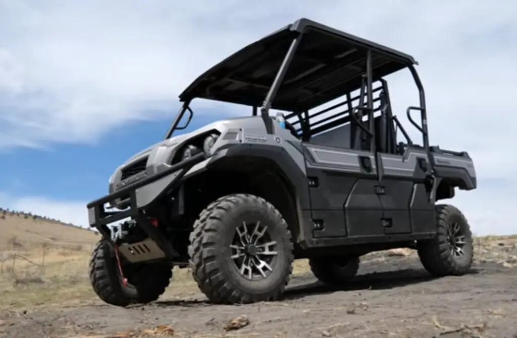 A Kawasaki mule pro FXT is parked on a dirt field. In the background there is beautiful blue sky.