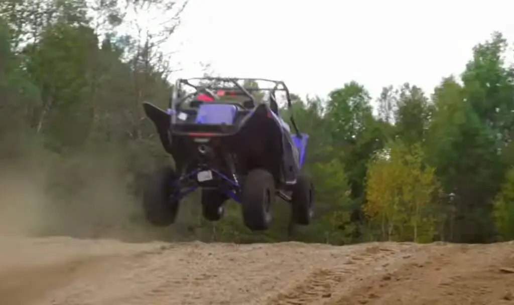 A Yamaha YXZ is being driven through a dirt and dusty road.