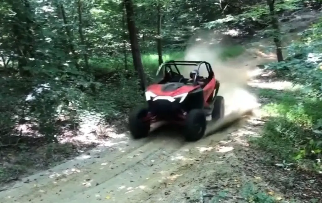 A red UTV is being driven through a dirt jungle terrain.