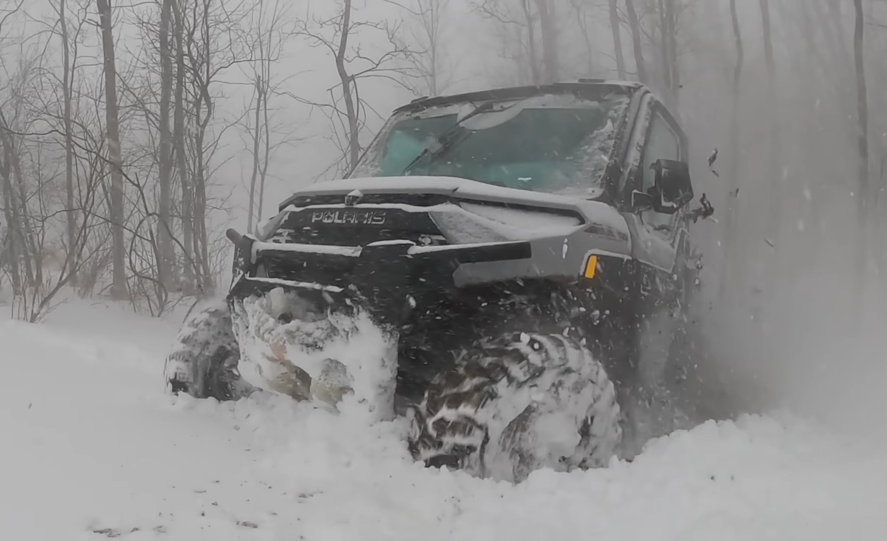 A Polaris Ranger NorthStar is being driven through a deep snow road.