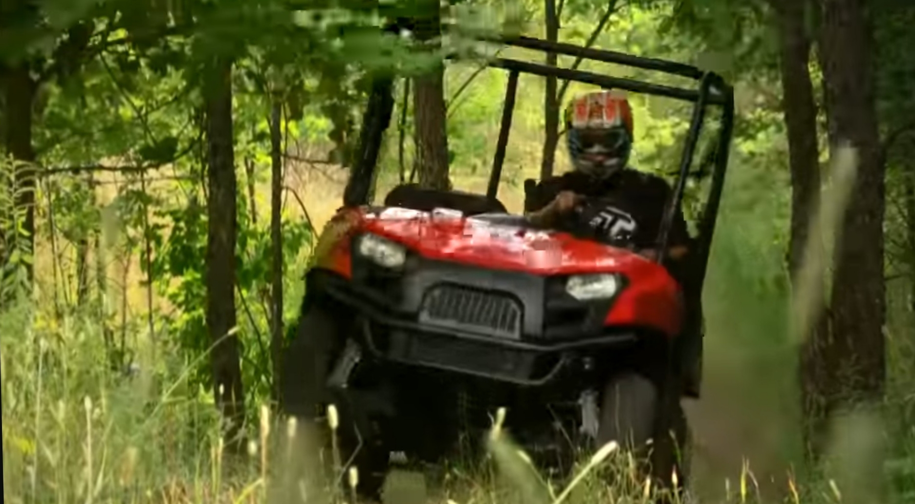 A Polaris Ranger 500 is being driven through a jungle terrain.