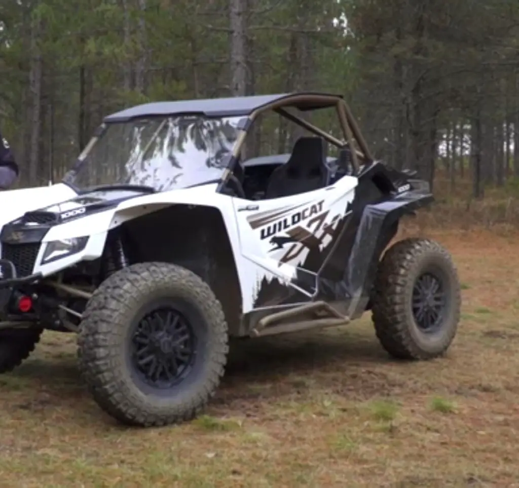 An Arctic Cat Wildcat XX is parked in front of a forest.