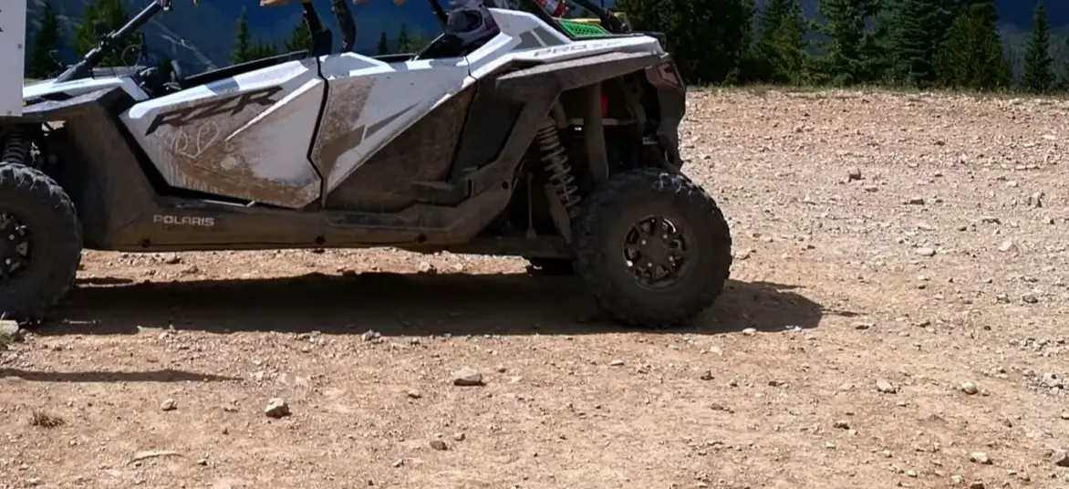 A Polaris RZR is parked on the top of a hill.