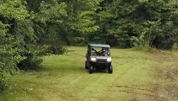 A Polaris Ranger 1000 is being driven through a green field.