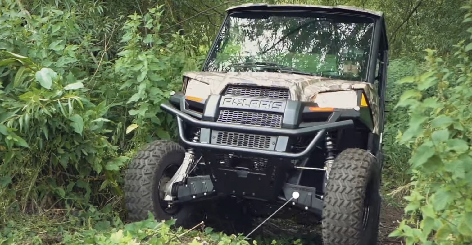 A Polaris Ranger EV is being driven through a jungle terrain.