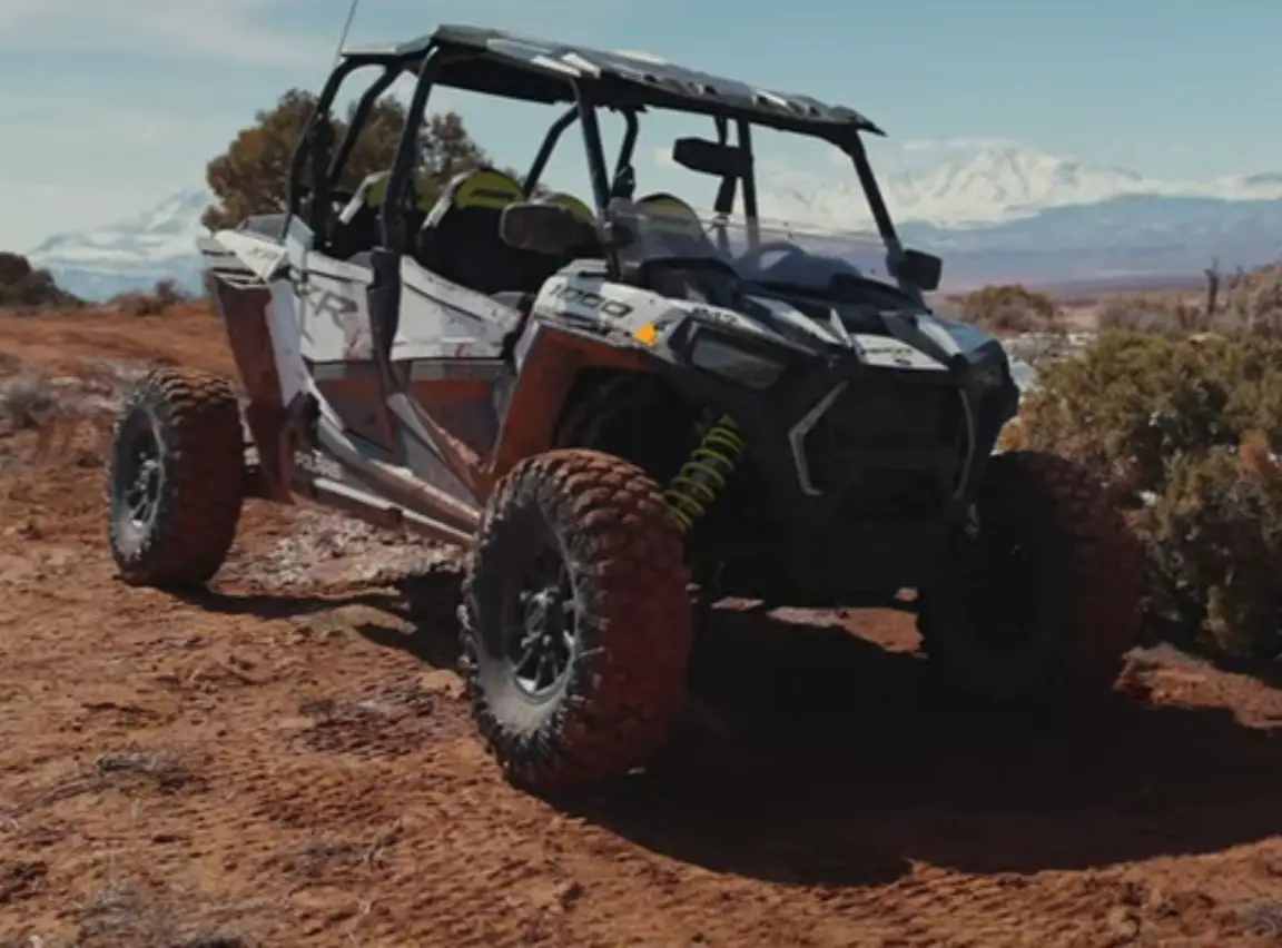 A Polaris RZR 1000 is parked on the top of a hill.