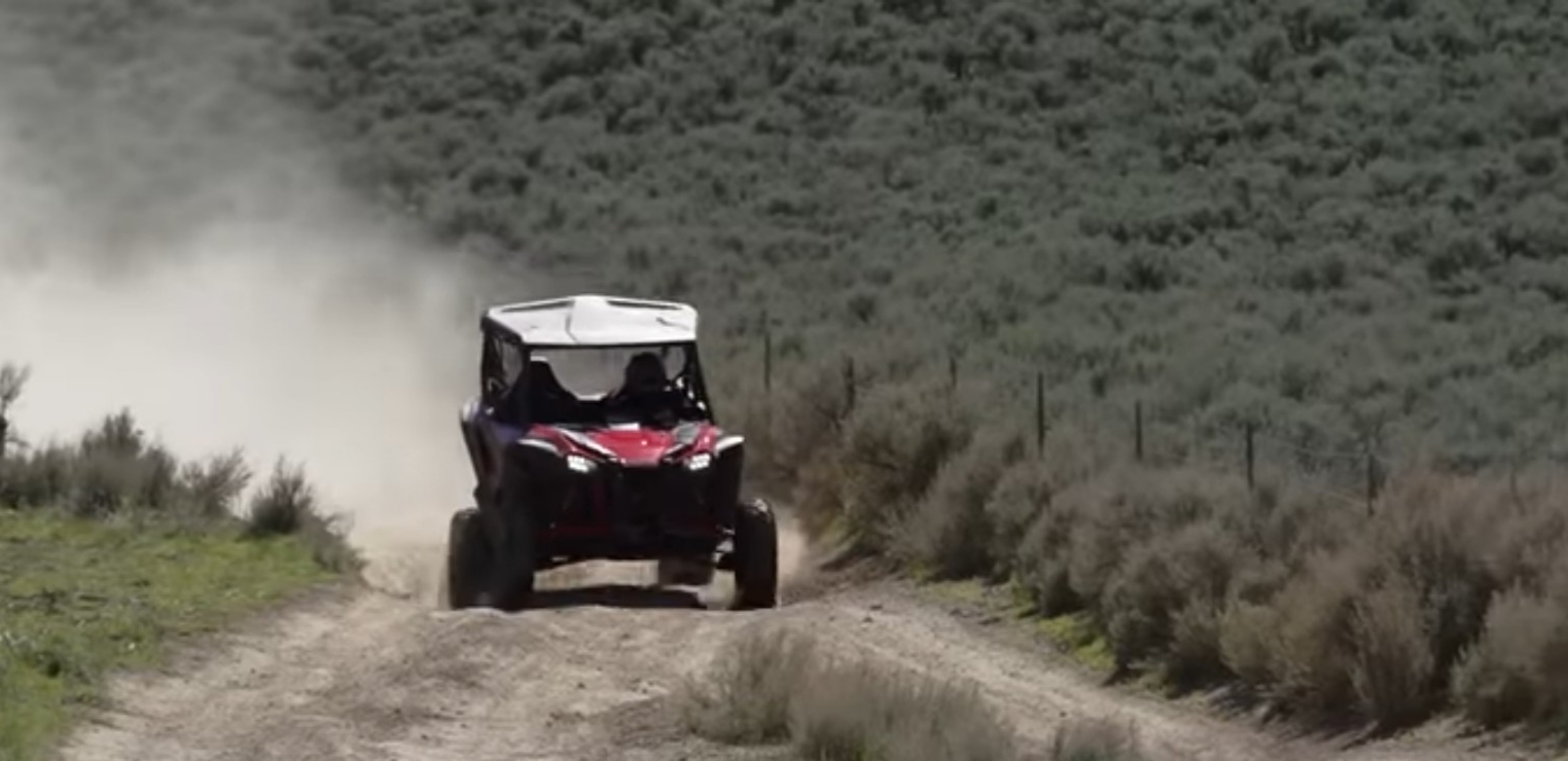 A Honda Talon 1000R is being driven through a dusty road.