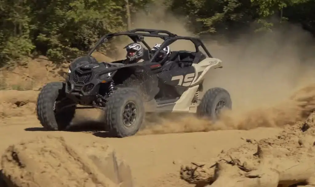 A Can-Am Maverick X3 is being driven through a New York dirt road.