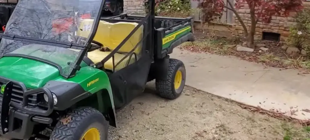 A John Deere HPX615E is parked in front of a house.