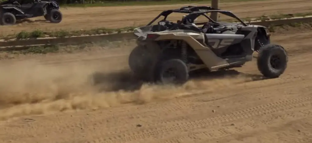 A Can-am Maverick is being driven through a dirt road.