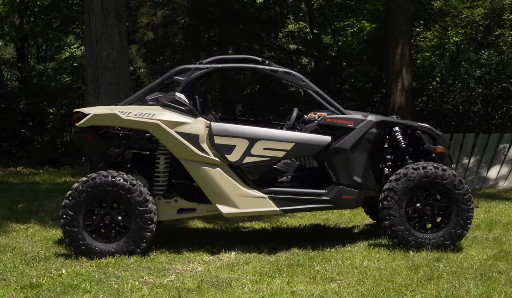 A Can-Am Maverick X3 is parked on a grassy field.