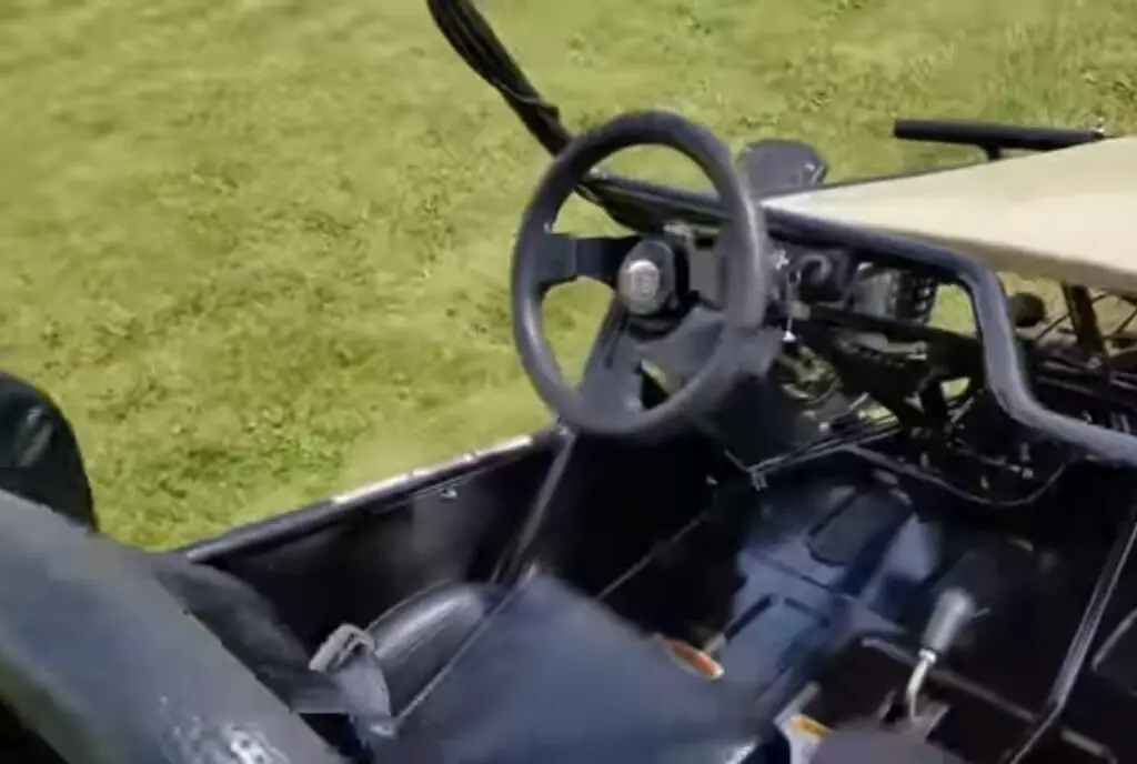 A child UTV is parked in a green field.