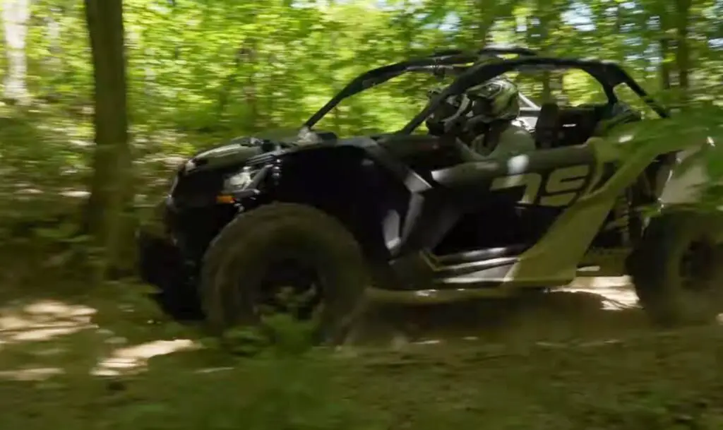 A Can-am Maverick X3 is being driven through a jungle terrain.