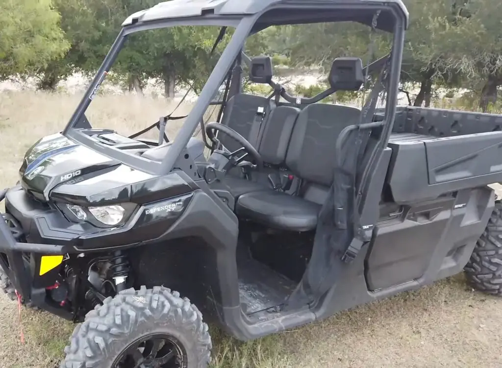 A Can-am defender pro XT is parked in a dry grass field. 