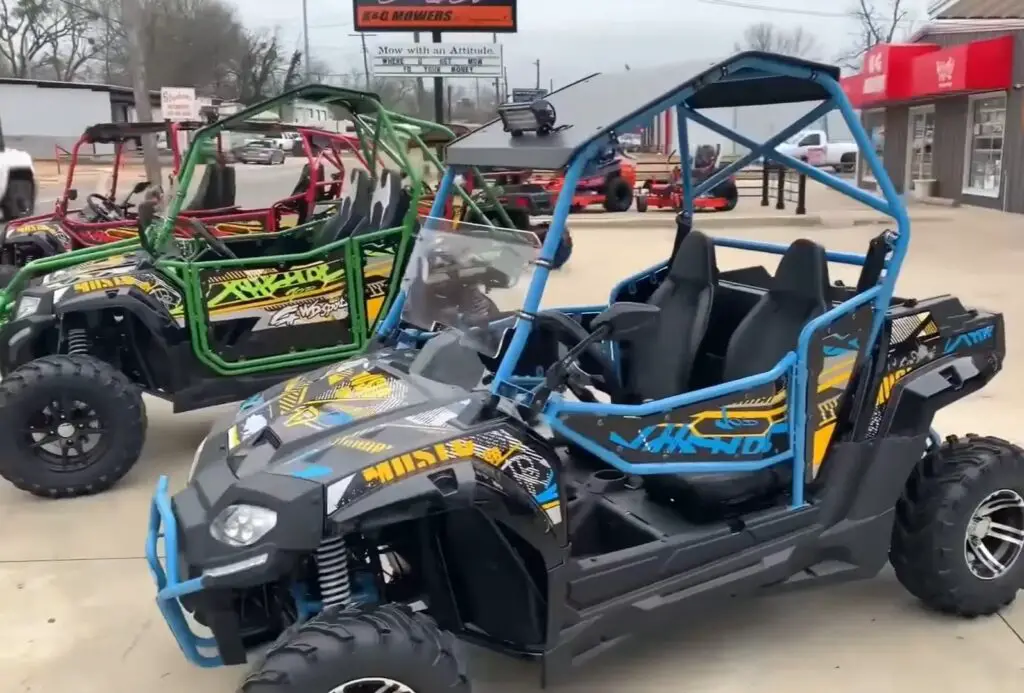 There UTVs parked in a row in front of a showroom.