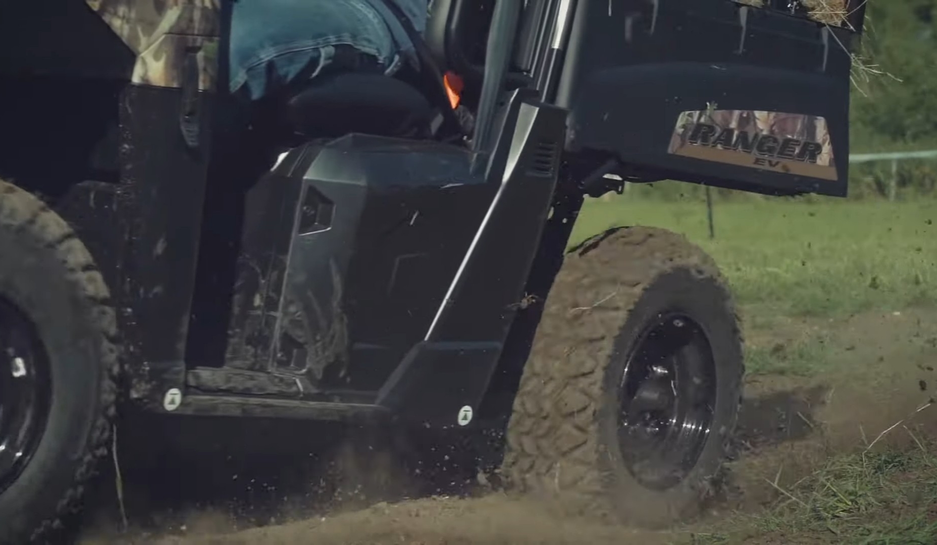 A Polaris Ranger EV with loaded dump bed is being driven through a dirt road.