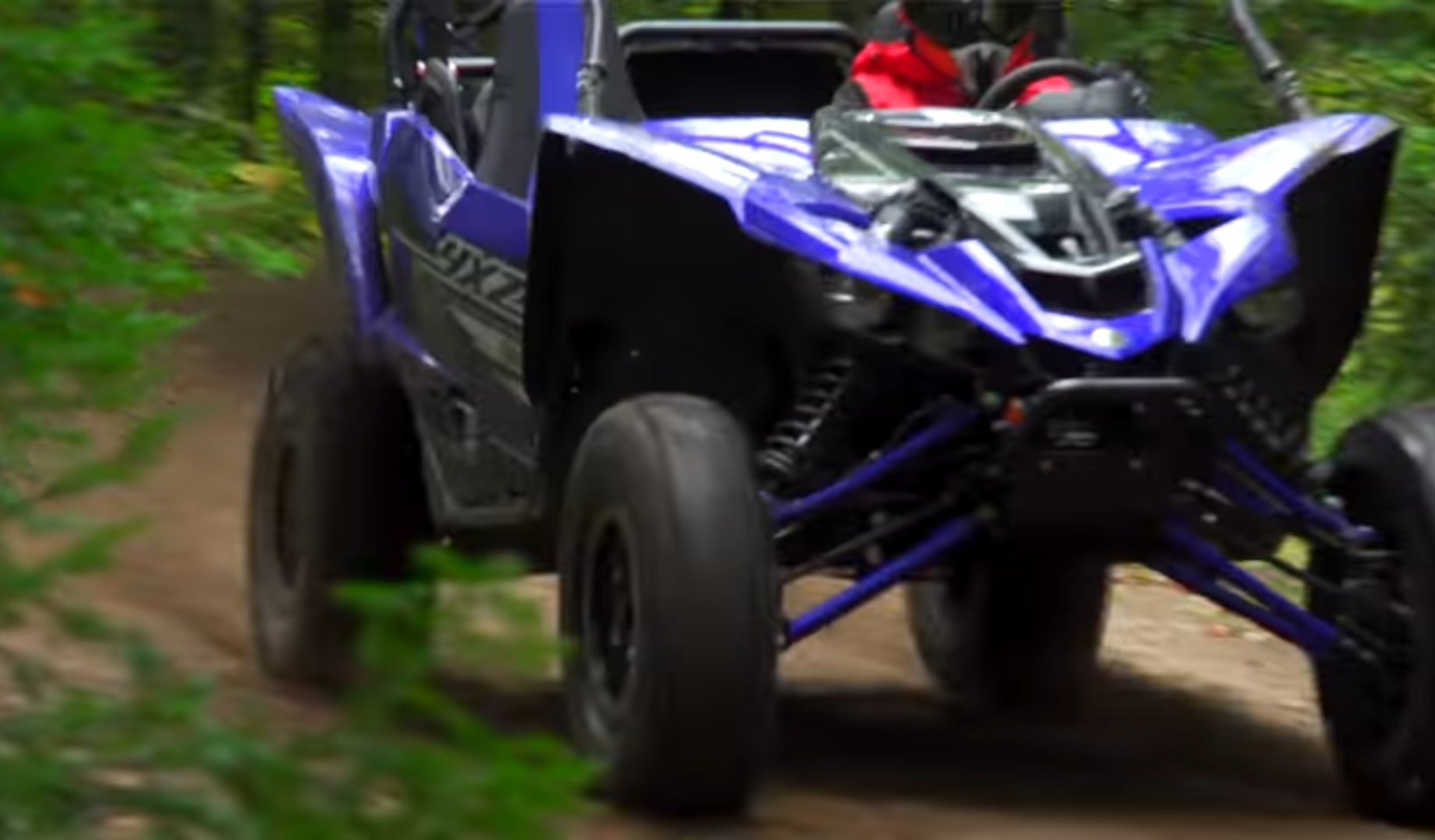 Yamaha YXZ1000R is being driven through a green jungle terrain.