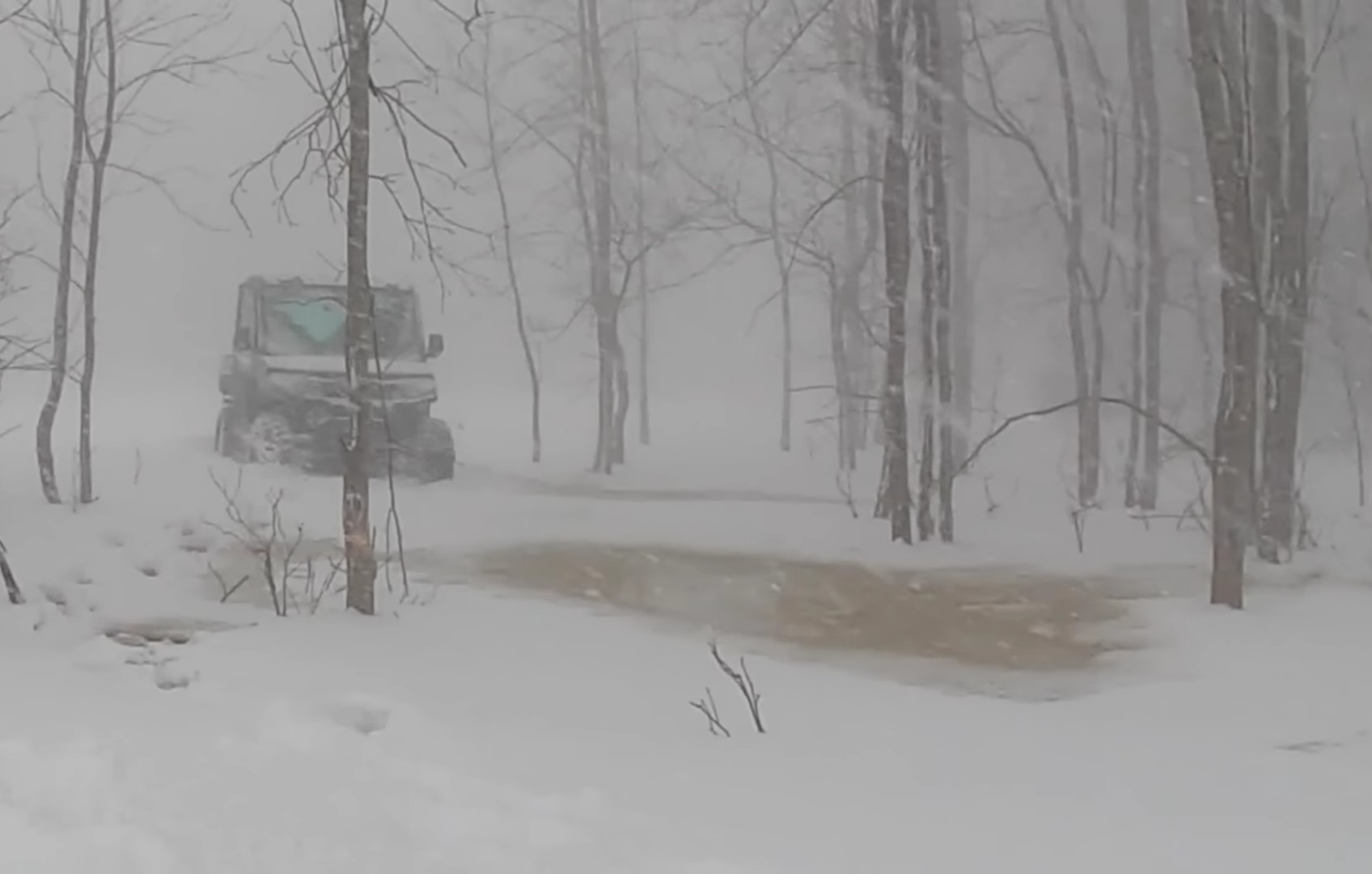 A Polaris Ranger NorthStar is being driven through a snow forest trail.