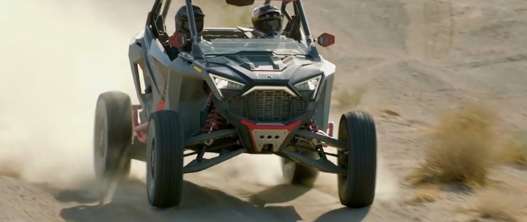 A Polaris UTV is being driven through a dirt road.