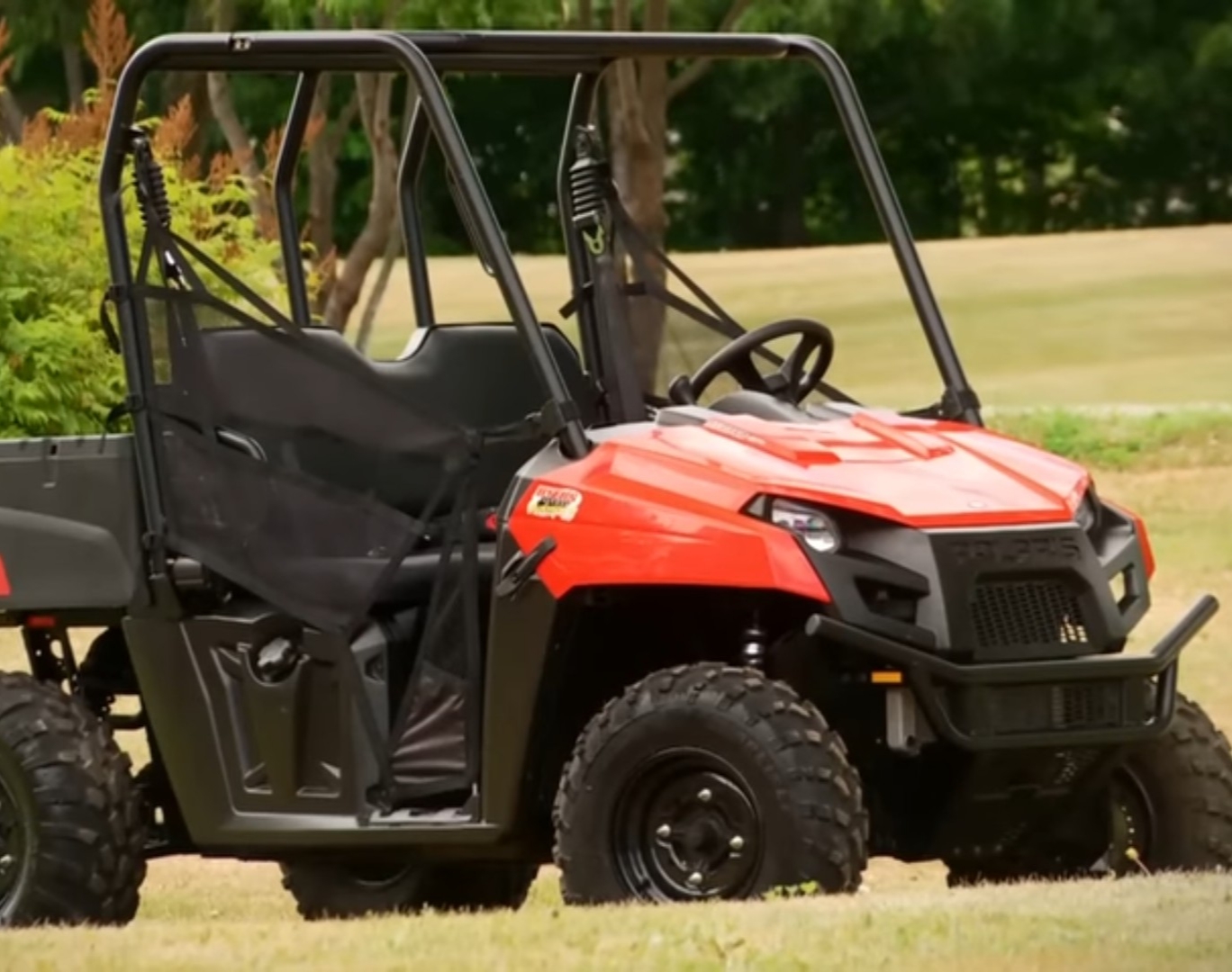 A Polaris Ranger 500 is parked in a green field.