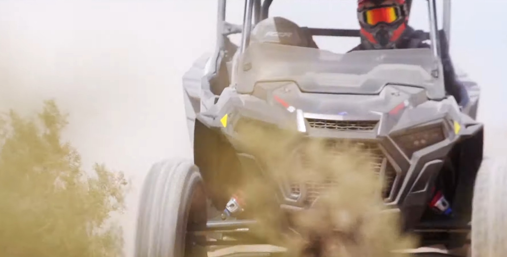 A Polaris RZR Turbo S is being driven through a dirt road.