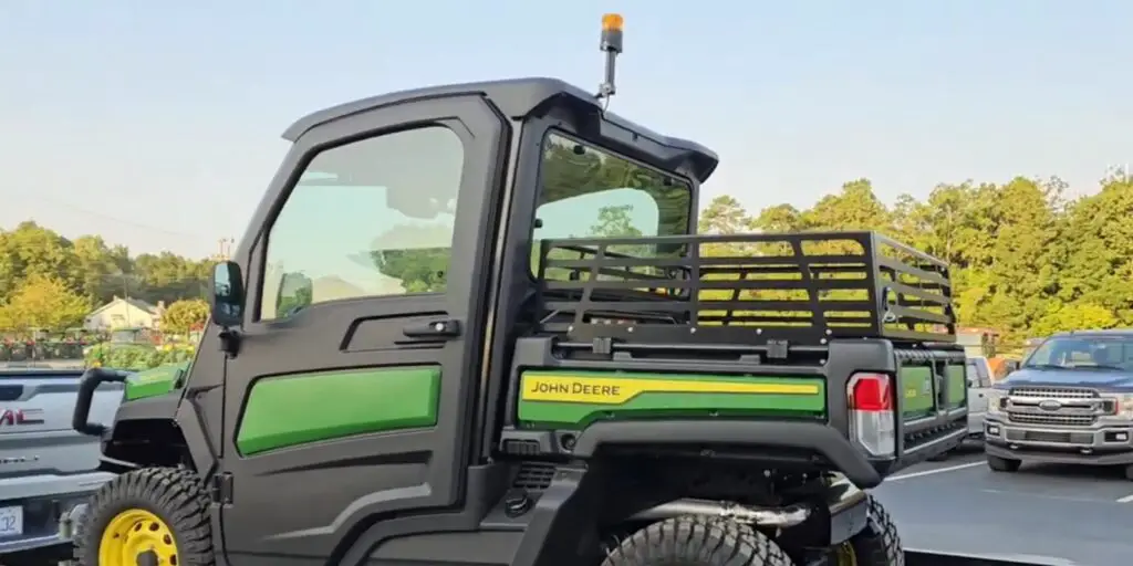 A Gator John Deere XUV835M HVAC is parked in a parking lot. In the background there are some cars are parked in a row.