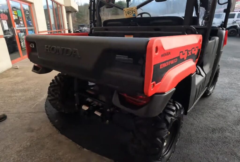 A Honda Big Red MUV is parked outside of a showroom.