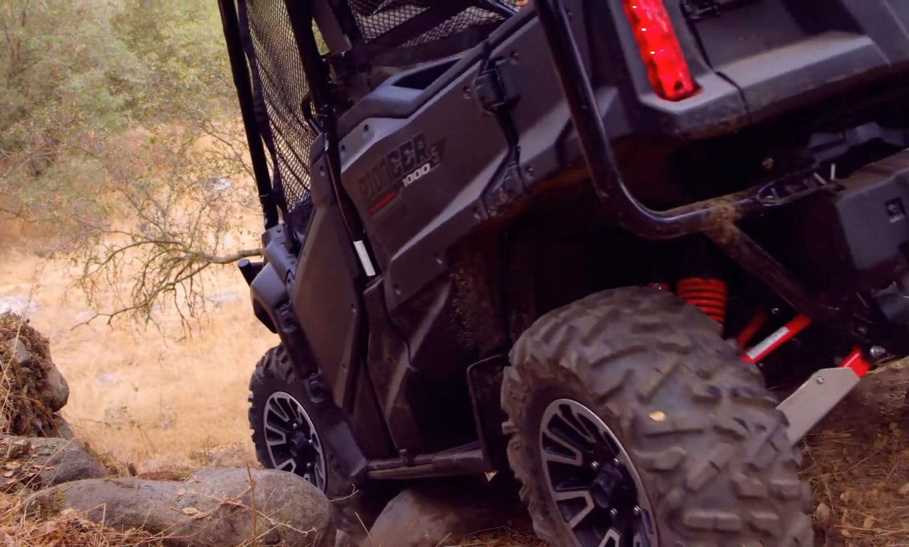 A Honda Pioneer 1000-5 LE is being driven through a rocky terrain.