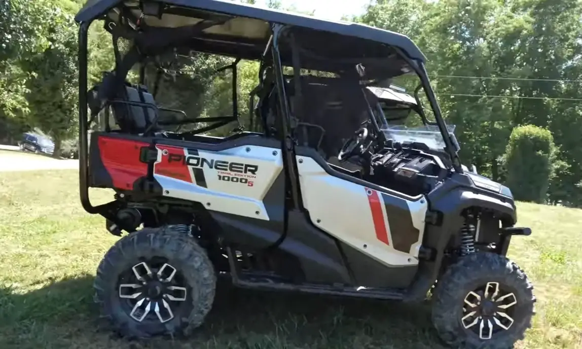 A Honda Pioneer 1000 is parked in a green field.