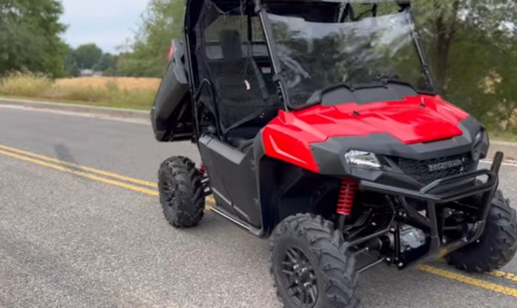 A Honda Pioneer 700 is parked on a clean concrete road.