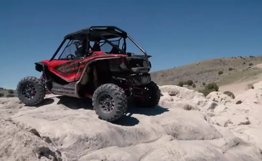 A Honda Talon 1000R is parked on the top of a rocky hill.